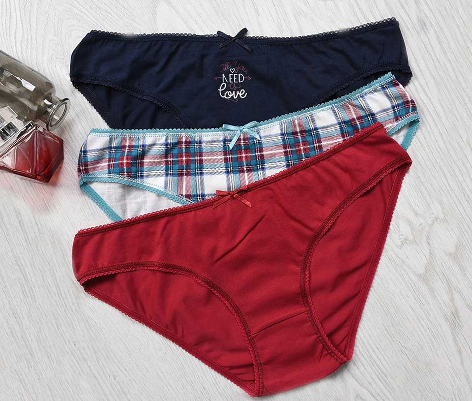 tri gaćice u tamnoplavoj, kariranoj i crvenoj boji poređane na svetloj drvenoj podlozi